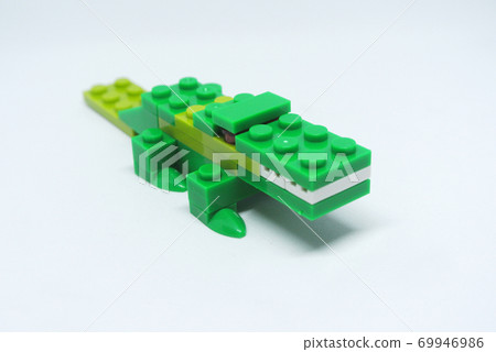 The shape of a green crocodile is made from colorful plastic toy bricks. 69946986