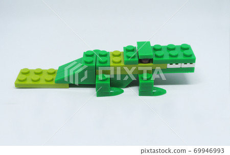 The shape of a green crocodile is made from colorful plastic toy bricks. 69946993