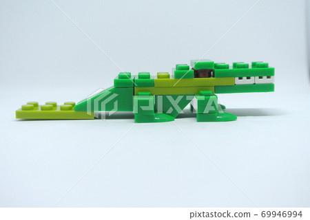 The shape of a green crocodile is made from colorful plastic toy bricks. The shape of a green crocodile is made from colorful plastic toy bricks. 69946994