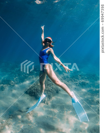 Happy freediver woman with New year cap glides underwater in blue ocean. Christmas holidays concept Happy freediver woman with New year cap glides underwater in blue ocean. Christmas holidays concept 69947398