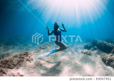 Happy freediver woman with New year cap glides underwater in blue ocean. Christmas holidays concept Happy freediver woman with New year cap glides underwater in blue ocean. Christmas holidays concept 69947401