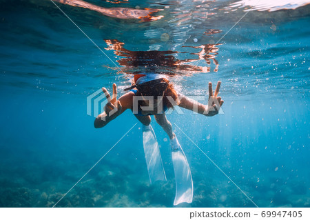 Happy freediver woman with New year cap glides underwater in blue ocean. Christmas holidays concept Happy freediver woman with New year cap glides underwater in blue ocean. Christmas holidays concept 69947405