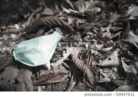 Used surgical mask lying on dry leaves in the field Used surgical mask lying on dry leaves in the field 69947632