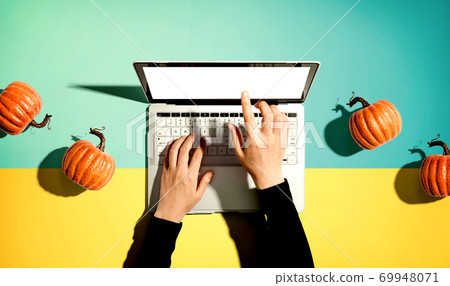 Autumn pumpkins with person using a laptop computer Autumn pumpkins with person using a laptop computer 69948071