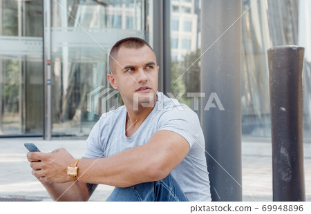 Guy with a mobile phone in his hands. Man with a watch and a phone. 69948896