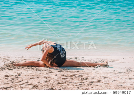 Active little girl at beach having a lot of fun. Cute kid making sporty exercises on the seashore 69949017