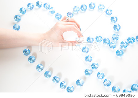 Hand of a woman with an engagement ring picking a heart stone 69949080