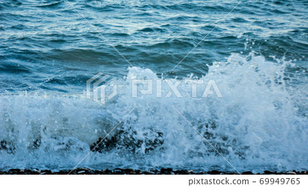 The waves breaking on a stony beach. Mediterranean sea waves crashing on the rocks at the beach 69949765