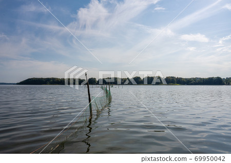 Beautiful scenery of a fishing net in a lake one of the latest days of summer. Picture from Ringsjon, Scania, southern Sweden Beautiful scenery of a fishing net in a lake one of the latest days of summer. Picture from Ringsjon, Scania, southern Sweden 69950042
