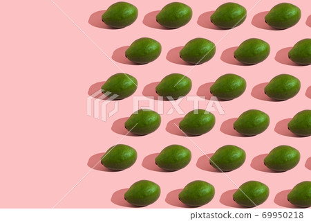 Trending style pattern of a whole green avocado on a pink background with hard light. Creative food texture. Trending style pattern of a whole green avocado on a pink background with hard light. Creative food texture. 69950218