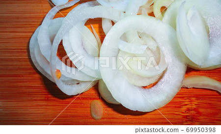 Raw sliced white onion on wooden chopping board ready to cook Raw sliced white onion on wooden chopping board ready to cook 69950398