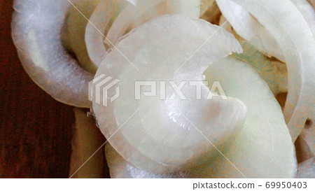 Raw sliced white onion on wooden chopping board ready to cook 69950403