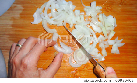Raw sliced white onion on wooden chopping board ready to cook 69950405