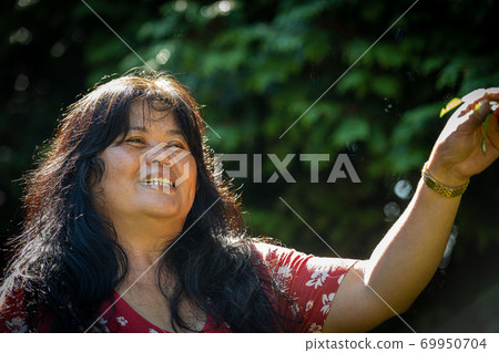 Closeup picture of a middle-aged, in her 50s, Asian woman with soap bubbles. Green background Closeup picture of a middle-aged, in her 50s, Asian woman with soap bubbles. Green background 69950704