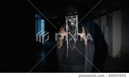 Scary man face in carnival skull Halloween makeup of skeleton looking creepy at camera on parking Scary man face in carnival skull Halloween makeup of skeleton looking creepy at camera on parking 69950956