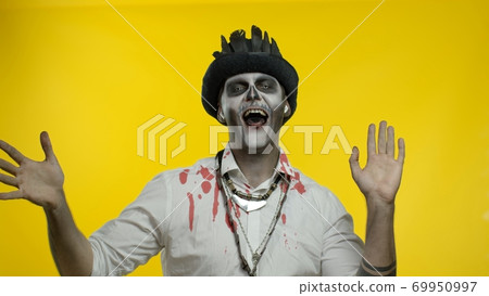 Scary guy in costume of Halloween skeleton wearing earphones, listening music, dancing, celebrating 69950997