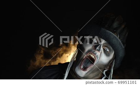 Creepy, crazy man with skeleton makeup. Guy making angry faces, shaking head, showing tongue Creepy, crazy man with skeleton makeup. Guy making angry faces, shaking head, showing tongue 69951101