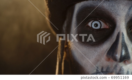 Close-up shot of face in skeleton Halloween makeup opening eyes with white pupil, trying to scare Close-up shot of face in skeleton Halloween makeup opening eyes with white pupil, trying to scare 69951169