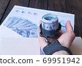 man's handcuffed hand holds twisted money against a background of hundred dollar bills in an envelope 69951942