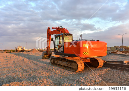 Excavator during road work at construction site Excavator during road work at construction site 69953156
