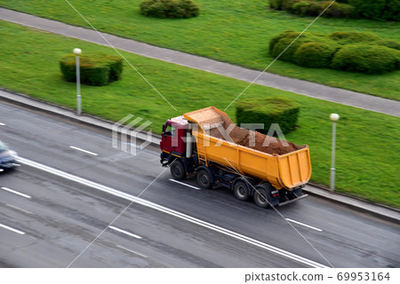 Dump truck carries sand along a road in a city. Dump truck carries sand along a road in a city. 69953164