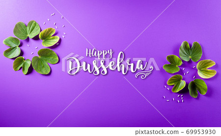 Happy Dussehra. Green leaf and rice on purple pastel background. Dussehra Indian Festival concept. Happy Dussehra. Green leaf and rice on purple pastel background. Dussehra Indian Festival concept. 69953930