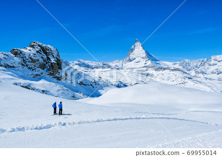 Two Skier see beautiful view of snow mountain Matterhorn peak, Zermatt, Switzerland. 69955014