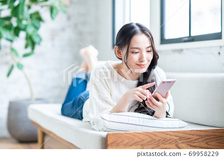 在客廳裡使用智能手機的年輕女子 在客廳裡使用智能手機的年輕女子 69958229
