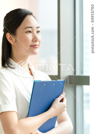 Female nurse looking out the window [Portrait] 69958760