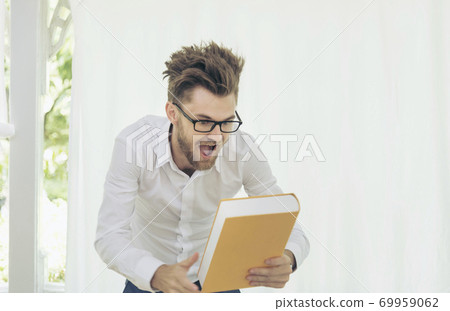 Caucasian man holding text book study hard surprise in content. education concept Caucasian man holding text book study hard surprise in content. education concept 69959062