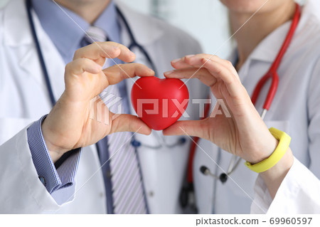 Doctors man and woman with phonendoscope hold red heart in their hand 69960597