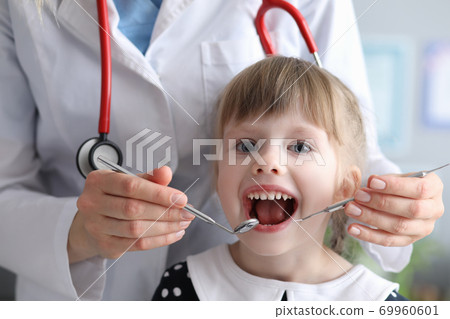Dentist doctor with stethoscope examines teeth of little girl in clinic 69960601