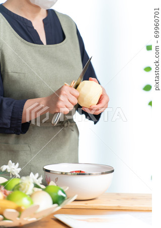 A woman wearing a mask and peeling an apple A woman wearing a mask and peeling an apple 69960701