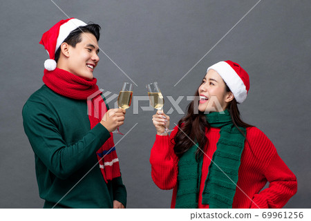 Happy Asian couple drinking champagne celebrating Christmas Happy Asian couple drinking champagne celebrating Christmas 69961256