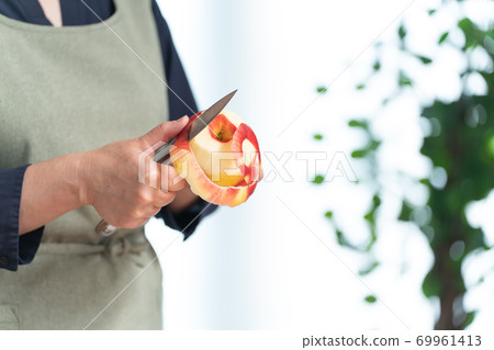 Hands of a woman peeling an apple Hands of a woman peeling an apple 69961413
