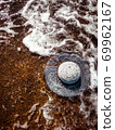 A white straw hat lies on the sand by the water. Sea beach on a summer sunny day. Sea vacation concept. Copy space. High quality photo 69962167