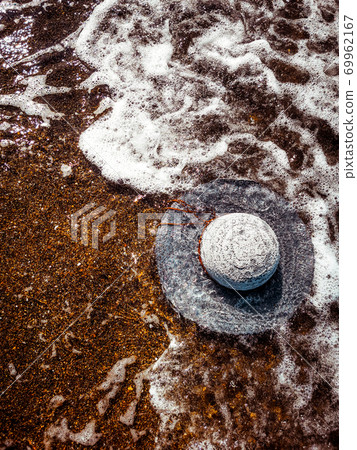 A white straw hat lies on the sand by the water. Sea beach on a summer sunny day. Sea vacation concept. Copy space. High quality photo A white straw hat lies on the sand by the water. Sea beach on a summer sunny day. Sea vacation concept. Copy space. High quality photo 69962167