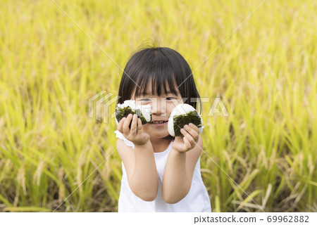 一個孩子在秋天的稻田裡用米耳吃美味的新米飯 一個孩子在秋天的稻田裡用米耳吃美味的新米飯 69962882