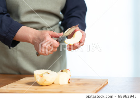A woman's hand cutting an apple A woman's hand cutting an apple 69962943