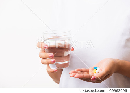 Woman hold pill drugs in hand ready take medicines with a glass of water Woman hold pill drugs in hand ready take medicines with a glass of water 69962996