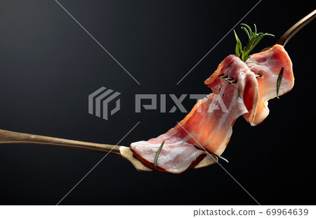 Bacon slices and rosemary on a fork. 69964639