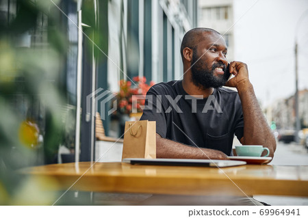 Contented man enjoying pleasant phone talk in the city Contented man enjoying pleasant phone talk in the city 69964941