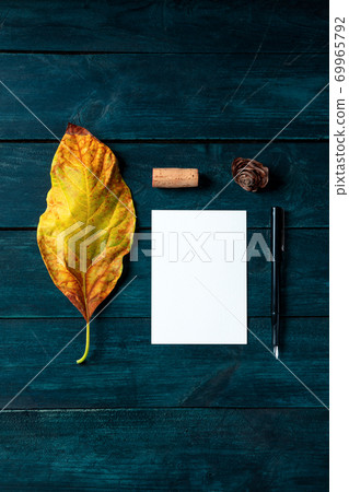 Autumn stationery mockup, a vertical A5 greeting card or invitation, shot from the top on a dark blue wooden background with a wine cork 69965792