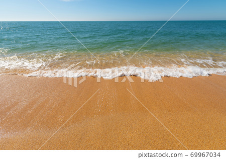 Morning turquoise sea and waves with white foam roll over the yellow golden sand of the beach. Ocean coast vacation concept 69967034