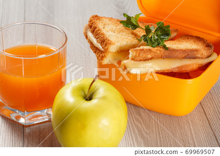 Yellow lunch box with toasted slices of bread, cheese and parsley, green apple. Yellow lunch box with toasted slices of bread, cheese and parsley, green apple. 69969507