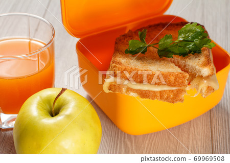 Yellow lunch box with toasted slices of bread, cheese and parsley, green apple. Yellow lunch box with toasted slices of bread, cheese and parsley, green apple. 69969508
