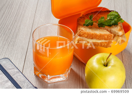 Yellow lunch box with toasted slices of bread, cheese and parsley, green apple. Yellow lunch box with toasted slices of bread, cheese and parsley, green apple. 69969509