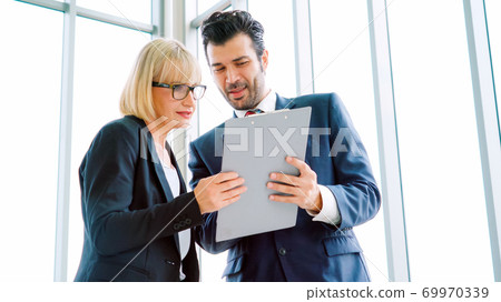 Two business people talk project strategy at office Two business people talk project strategy at office 69970339