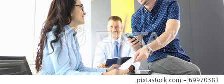Businesswoman and businessmen in office are sitting at table, smiling and discussing work processes 69970381