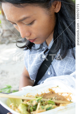 A young Asian woman eat typical Burmese food on a street in Mandalay, Myanmar. A young Asian woman eat typical Burmese food on a street in Mandalay, Myanmar. 69970771